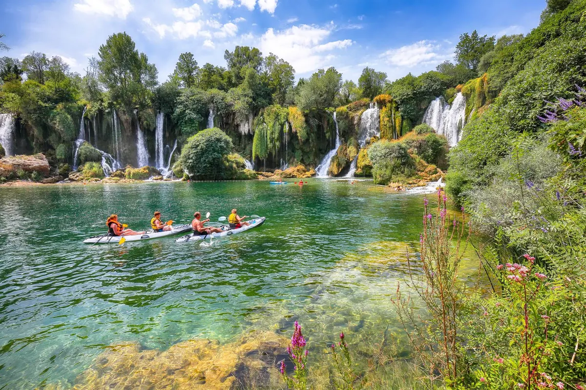 Kravice Waterfalls with kayakers on turquoise water